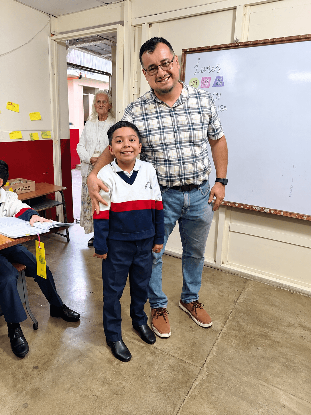 A student and an adult visitor smiling together in a classroom
