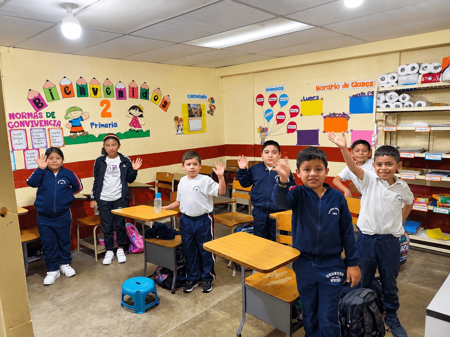 Students standing together beside their classroom desks