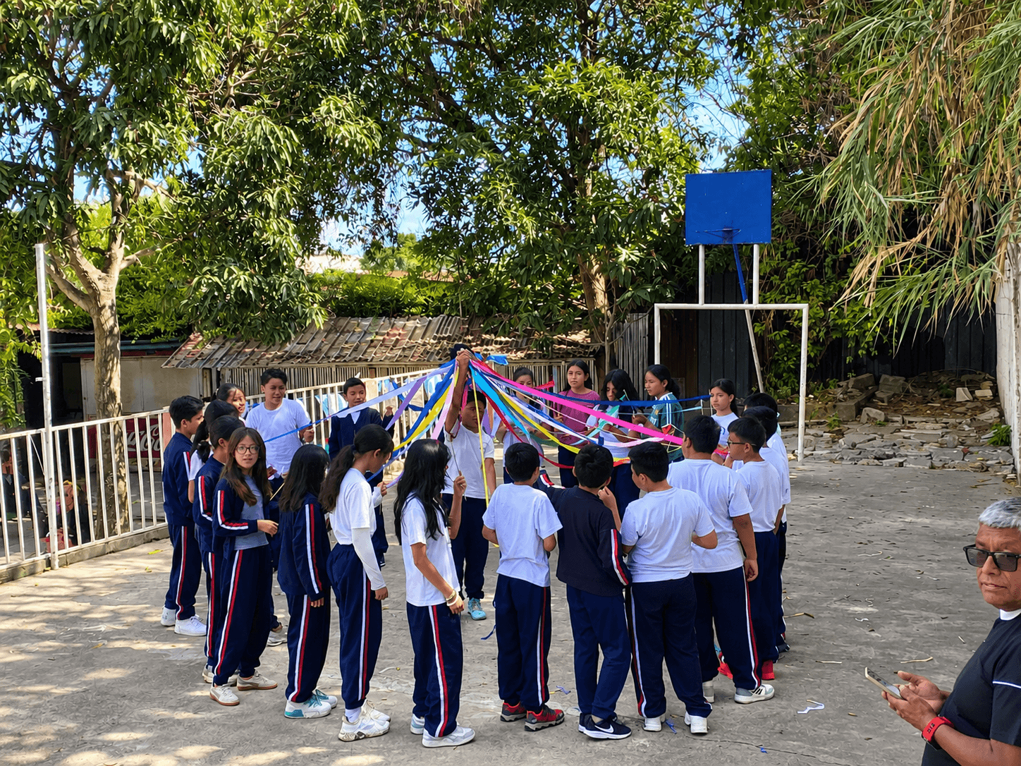 Students forming a circle with colorful ribbons in the school courtyard