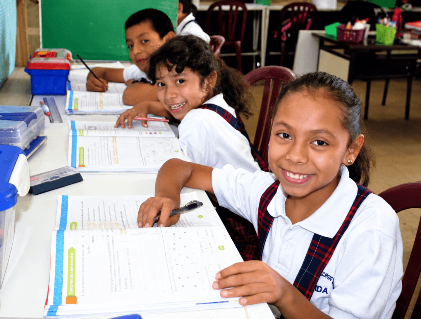 A student smiling as she works at her classroom desk
