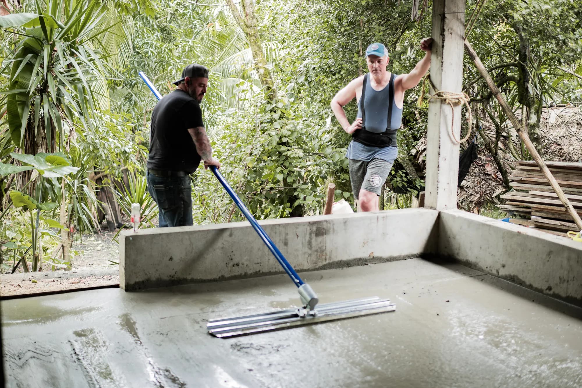 Los voluntarios alisan un nuevo piso de concreto en una casa familiar.