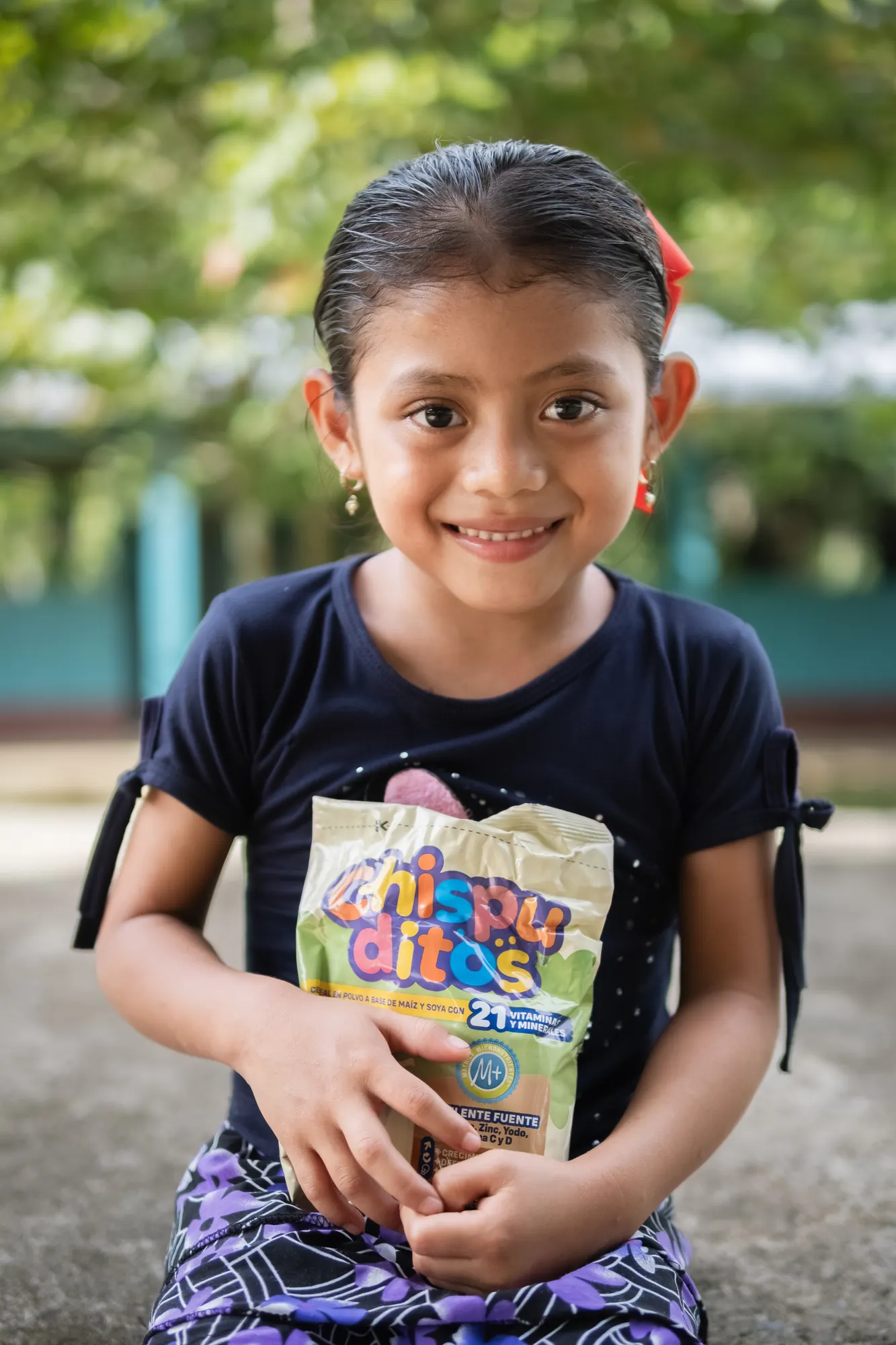 A young girl smiles with materials from a child nutrition program.