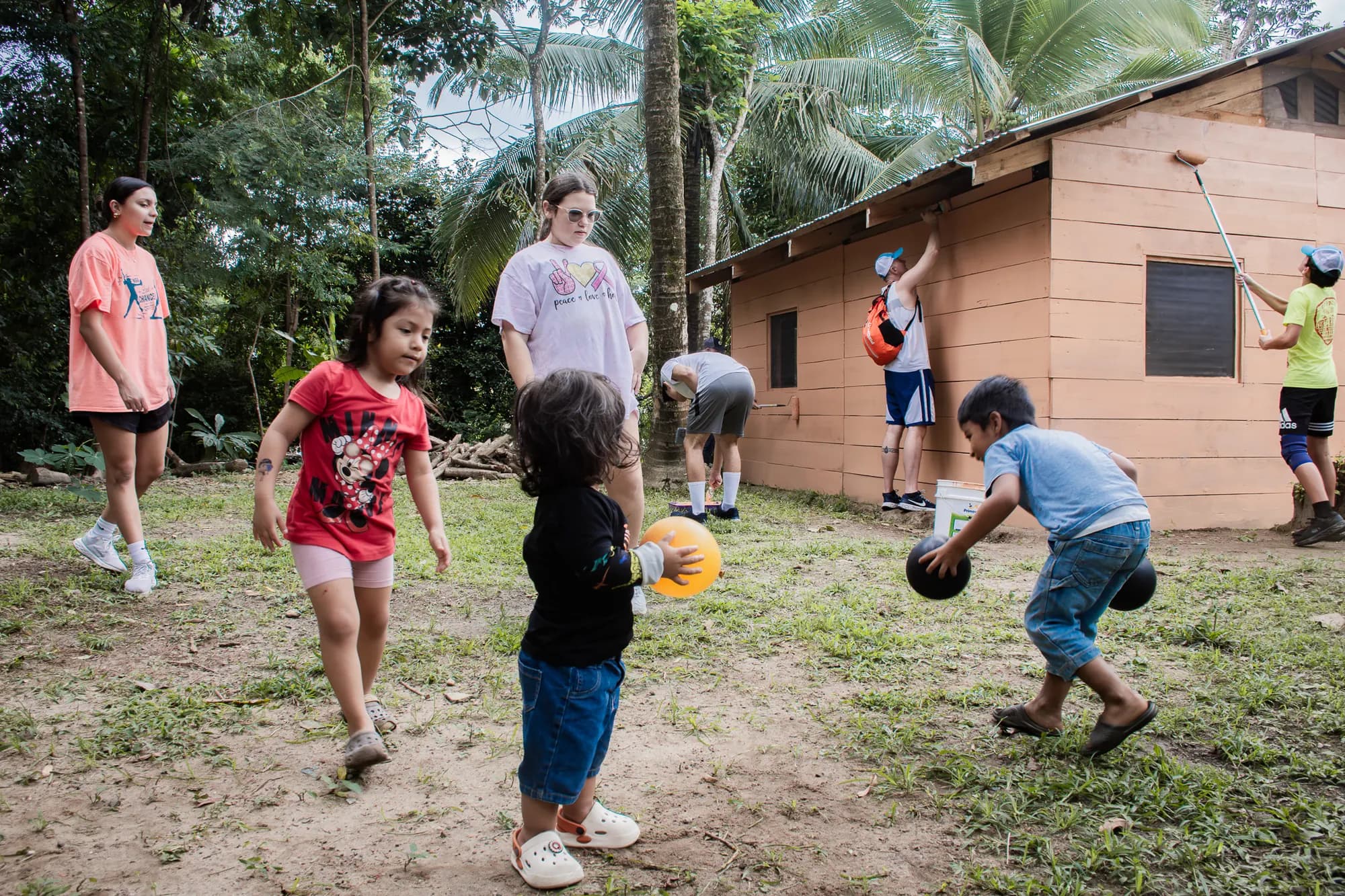 Visiting volunteers play with children outside a family home.