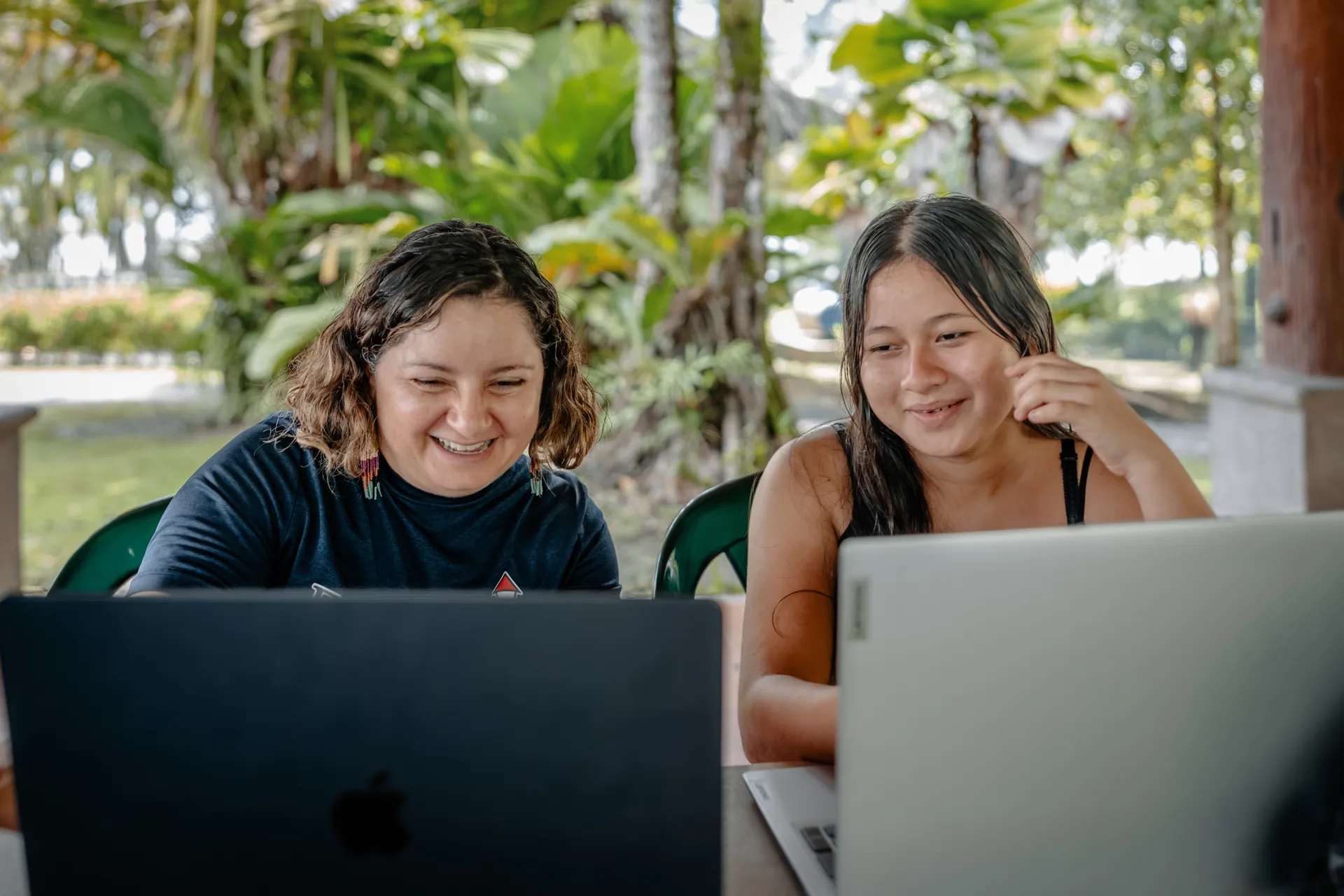 Two adult education students work side by side on laptop computers.