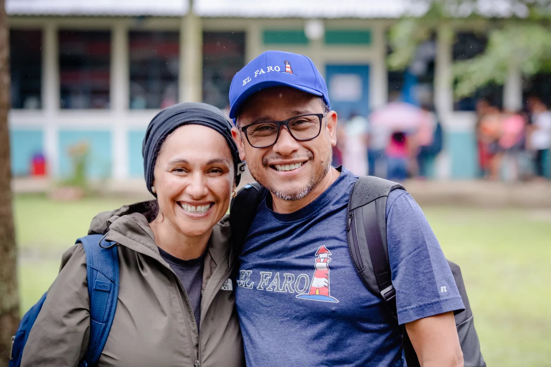 Dos voluntarios de El Faro sonríen juntos al aire libre.