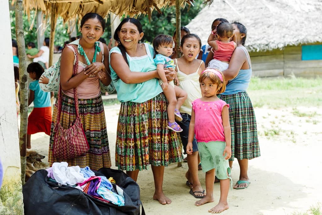 Mujeres y niños se reúnen durante una visita comunitaria de El Faro.