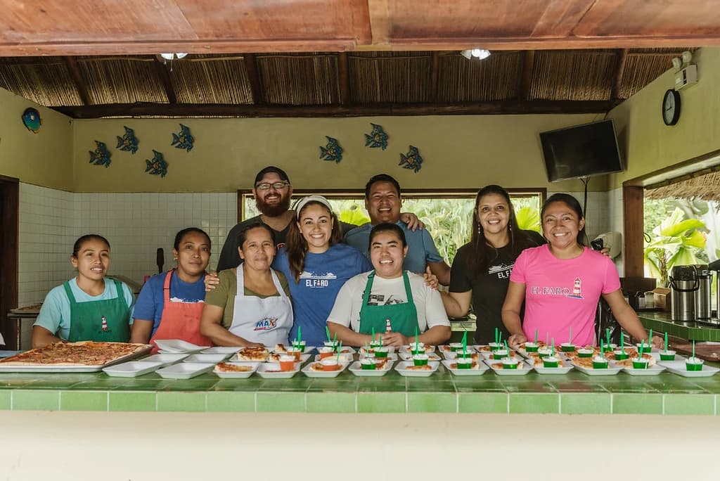 El equipo de hospitalidad posa detrás de una comida preparada.